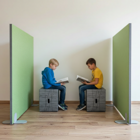 Zwei Kinder sitzen auf Xbrick® Hocker zwischen grünen Absorber-Stellwänden PET G25 und lesen Bücher in einer ruhigen Lernumgebung